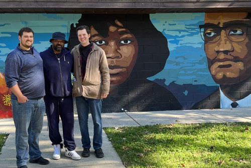 Group photo in front of mural in Malcom X park